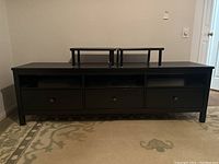 Front view of IKEA Hemnes dark espresso TV storage unit showing 3 drawers with round knobs and 3 open shelves above