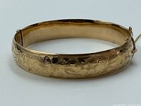 Front view of hinged bangle showing full floral and leaf engraving