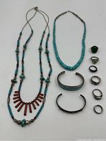 Overview of two necklaces, two cuff bracelets and six rings arranged on white background.