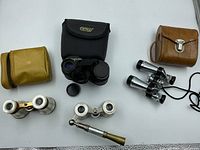 Overall view of all four optical devices including three vintage opera glasses and one modern binocular with cases
