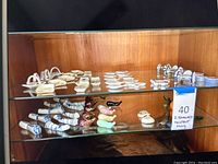 A display shelf showcasing multiple ceramic chopstick holders in various shapes including traditional blue and white patterns, animal shapes, and vegetable designs.
