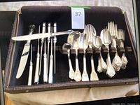 Case open showing carving knife at center top, six picks at top left and spoons and forks on right