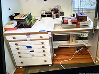 Full view of white wooden crafting sewing table on wheels showing storage drawers and work surface