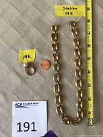 Top-down view of chain and ring with measurement tape and penny