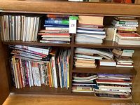 Wooden shelving filled with numerous Japanese books and magazines, some stacked horizontally and others vertically.