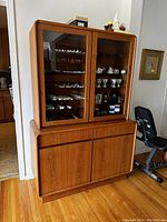 Front view showing overall cabinet with top glass section and bottom wooden storage.