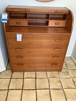 Front view of Mid Century style wooden secretary writing desk with roll-top open, showing workspace and compartments above drawers.