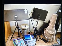 Overview of two black metal music stands, goblet drum, books and cases