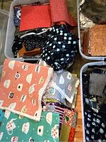 Photo showing containers filled with fabric swatches including teapot print fabrics and black with blue floral patterns