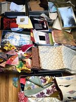 Overview of various fabric swatches, sewing materials, and related items laid out in boxes on the floor.