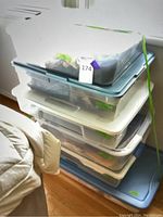 Stack of four plastic storage bins containing women's clothing items