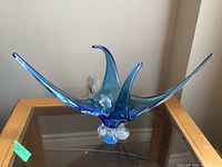 Front view of blue Chalet art glass sculpture on glass table showing elongated petals and clear base