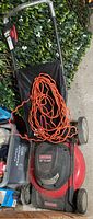 Top view of Craftsman electric lawn mower with orange extension cord coiled on it.