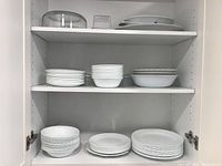 Corelle dishes including bowls and plates arranged on shelves inside a cabinet.