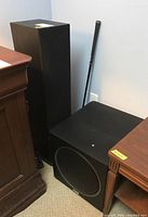 Full view of two black Polk Audio tower speakers and black Polk Audio powered subwoofer