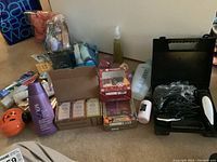 Wide shot of assorted toiletries, boxed soaps, Skin So Soft bath oil, jack-o-lantern soap dispenser, and Wahl clippers case on floor