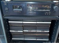 Front view of Nakamichi CR-1A cassette deck with cassette inserted and classical music tapes below.