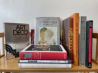 Photo of 10 different books about Art Deco furniture and decoration, arranged standing on a wooden bench.