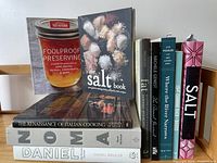 Photo of 10 assorted cookbooks on cuisine, preserving, and canning themes showing book spines and covers