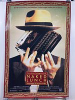 Front side of the "Naked Lunch" movie poster featuring a man holding a typewriter in front of his face with a red and gold border.