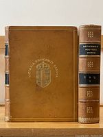 Two volumes of The Poetical Works of Robert Browning side by side showing full front cover and spine of Volume I. Full tan leather binding with Victoria University Canada gilt emblem and gilt lettering on spine.