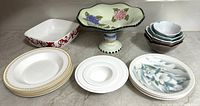 Photo of the full collection displaying various bowls, compote bowls, and plates with floral and gold accents