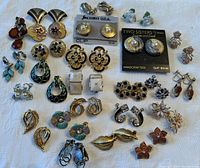 All earrings displayed together in a single image on a white fabric background.