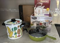 Image showing all the cookware items together on counter including the vintage San Ignacio pot, Zakarian skillet with lid, Cuisinart kettle in box, Pampered Chef pan, Parini pasta multicooker in box