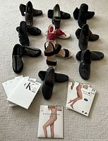 Multiple women's shoes arranged on carpet floor with 7 packages of pantyhose laid out in front. Shows variety of shoe styles and unopened hosiery packaging.