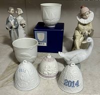 Overview photo showing all Lladro figurines and ceramic collectibles including Bride & Groom, Little Jester, Goose, three Annual Bells, and two Collector Society cups with one cup in original box.