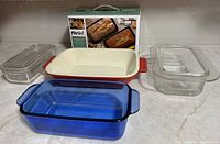 Overview of six baking dishes including glass, ceramic and stoneware, with Parini packaging in background.