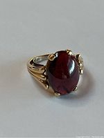 Front view of ring showing oval garnet cabochon in four-prong yellow gold setting