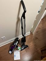 Bissell Magic Vac upright vacuum and Little Green Pet Stain Eraser handheld vacuum shown with manuals on wooden floor.
