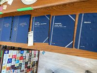 Five blue coin albums in a row on wooden surface