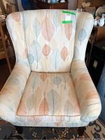 Front view of the leaf-patterned upholstered armchair, showing the cushion and rolled arms.