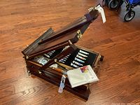 Photo of easel partially open showing top portion with some paint tubes and watercolor pad visible