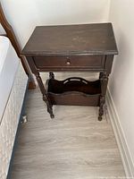 Full front view of the dark stained solid wood end table showing built-in magazine rack at the bottom and drawer above.