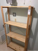 Front view of the light pine IKEA shelving unit showing four flat shelves and adjustable shelf holes on vertical side supports.