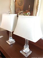 Pair of acrylic lamps with square clear acrylic bases and white fabric rectangular shades with clear acrylic finials.