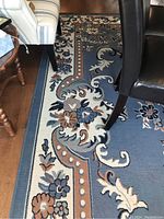 Overall view of rug under furniture showing floral scroll pattern and medallion design