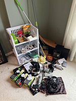 Full view of stacked white plastic bins containing multiple household and electronic items with mop and other supplies in corner of room.