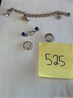 Overview of all six jewelry items displayed on white background including rings, earrings, and charm bracelet with two charms