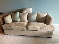 Front view of beige microfiber sofa bed with two seat cushions and four loose pillows.