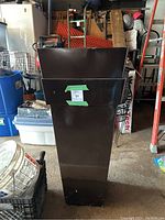 Tall brown metal planter with square opening and some denting along top edge, shown in garage setting