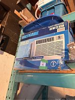 Frigidaire air conditioner in original box on a metal shelf in storage, showing product name, model, and cooling capacity details.