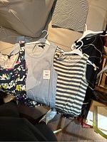 Four ladies summer sleeveless dresses laid out on a couch showing various patterns and colors.