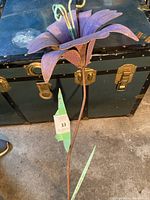 Close-up view of the purple metal flower petals and green leaves on the metal garden flower sculpture