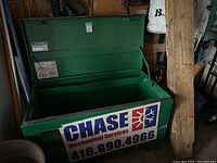 Front view of open green metal storage box with Chase Mechanical Services decal