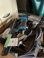 Photo showing a blue air stapler gun and two other pneumatic tools in a bag.