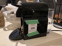 Front and side view of the black Nespresso coffee maker with retractable lever and drip tray.